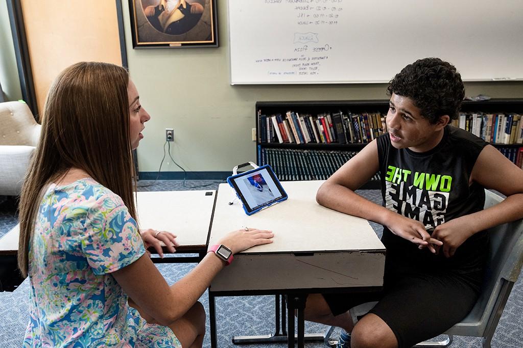 A U N E student shows an elementary school student how to use an i-pad